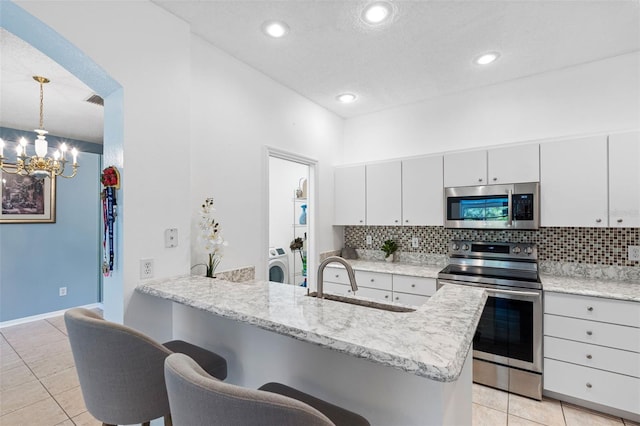 kitchen with kitchen peninsula, appliances with stainless steel finishes, decorative light fixtures, and sink