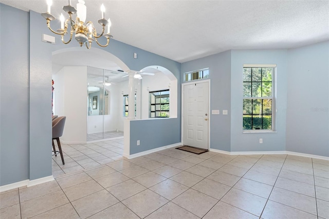 entryway featuring ceiling fan with notable chandelier, a textured ceiling, and light tile patterned floors