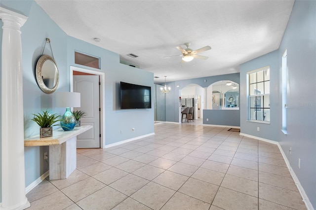 unfurnished living room with arched walkways, light tile patterned floors, a textured ceiling, baseboards, and ceiling fan with notable chandelier