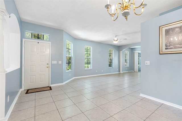 foyer entrance featuring light tile patterned floors, baseboards, arched walkways, a textured ceiling, and ceiling fan with notable chandelier