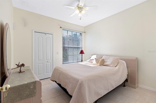 bedroom with a ceiling fan, a closet, baseboards, and light tile patterned floors