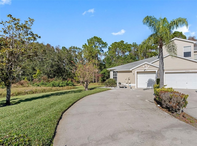 view of front of house with an attached garage, concrete driveway, and a front yard