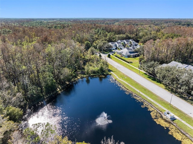 birds eye view of property featuring a water view and a wooded view