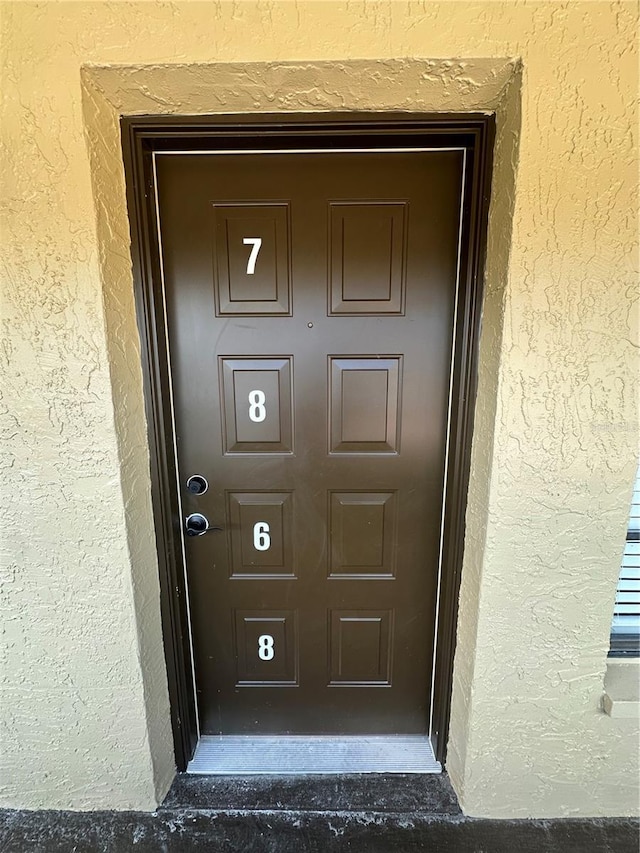 doorway to property featuring stucco siding