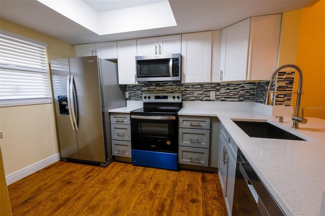 kitchen featuring white cabinets, appliances with stainless steel finishes, decorative backsplash, and sink