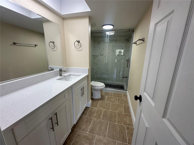 bathroom with a shower with door, vanity, and toilet