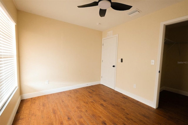 unfurnished bedroom featuring hardwood / wood-style flooring, ceiling fan, a spacious closet, and a closet