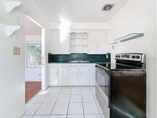 kitchen with light tile patterned flooring, tasteful backsplash, sink, white cabinets, and electric range