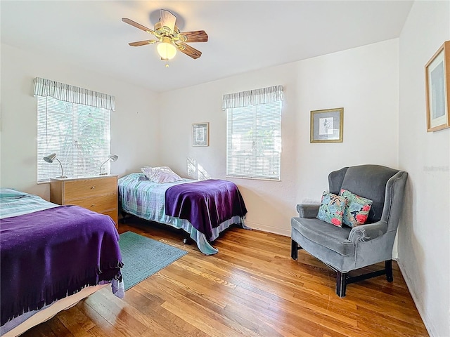 bedroom featuring hardwood / wood-style flooring, ceiling fan, and multiple windows