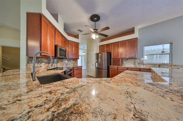 kitchen with appliances with stainless steel finishes, tasteful backsplash, light stone counters, and sink