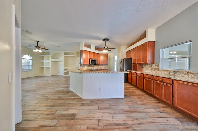 kitchen featuring hanging light fixtures, decorative backsplash, appliances with stainless steel finishes, light hardwood / wood-style floors, and light stone counters