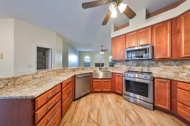 kitchen with backsplash, sink, light stone countertops, kitchen peninsula, and stainless steel appliances