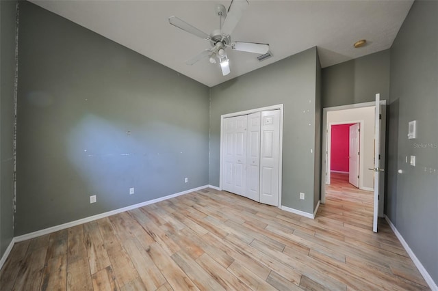 unfurnished bedroom with ceiling fan, a closet, light hardwood / wood-style floors, and vaulted ceiling