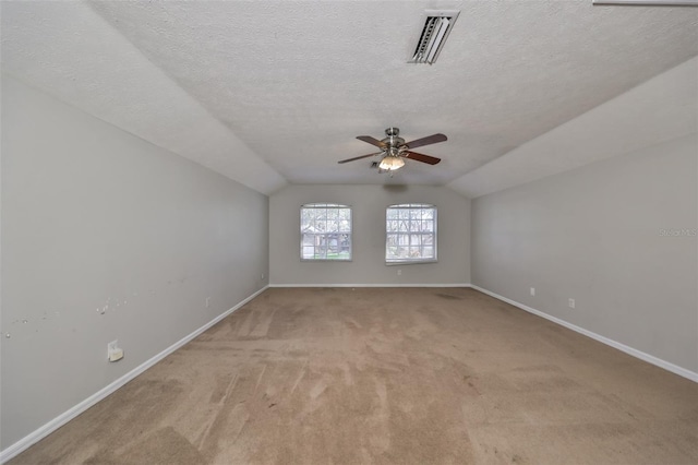 spare room with a textured ceiling, light carpet, ceiling fan, and vaulted ceiling