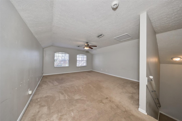 carpeted empty room with a textured ceiling, ceiling fan, and vaulted ceiling