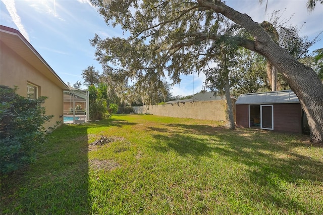 view of yard featuring a shed, a fenced in pool, and glass enclosure