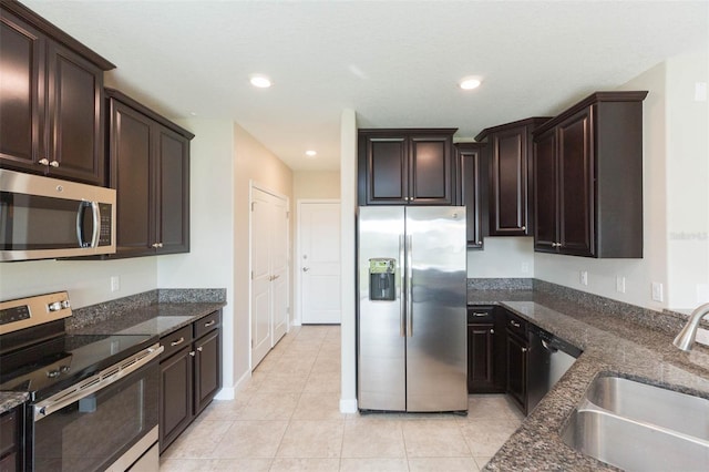 kitchen with sink, light tile patterned floors, stainless steel appliances, and dark brown cabinetry