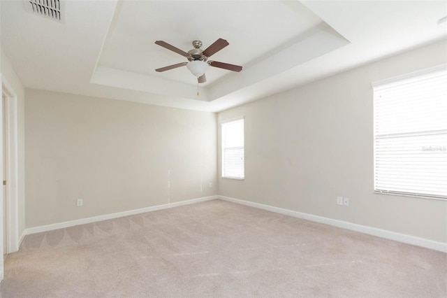 carpeted empty room with ceiling fan and a tray ceiling