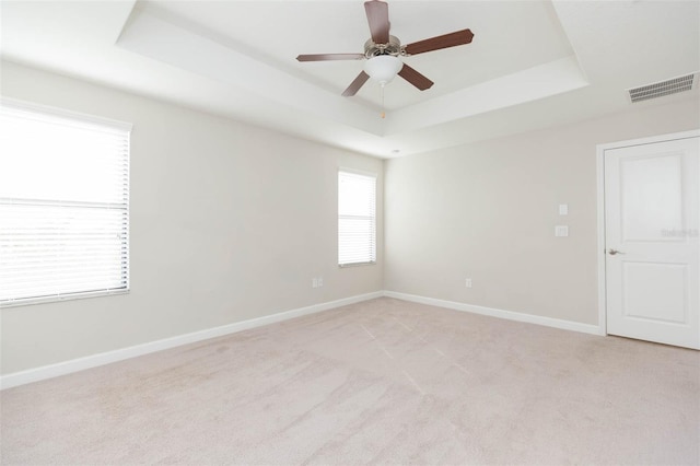 unfurnished room featuring a tray ceiling, ceiling fan, and light colored carpet