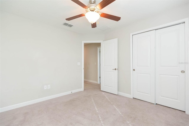 unfurnished bedroom featuring ceiling fan, light colored carpet, and a closet