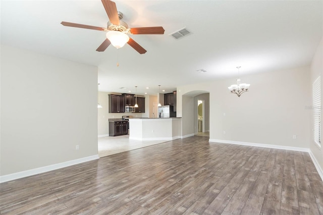 unfurnished living room featuring wood-type flooring and ceiling fan with notable chandelier