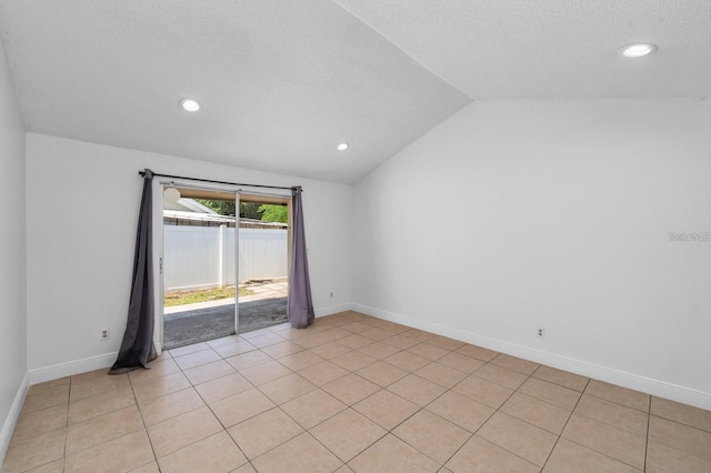 spare room featuring a textured ceiling, light tile patterned floors, and vaulted ceiling