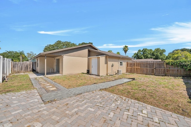 back of house featuring a patio, a yard, and a shed