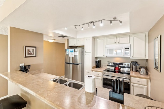 kitchen with sink, white cabinets, a raised ceiling, and stainless steel appliances