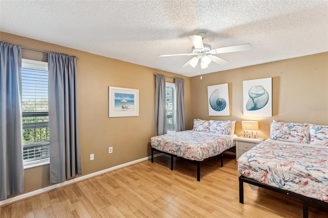 bedroom featuring ceiling fan, light wood-type flooring, and a textured ceiling