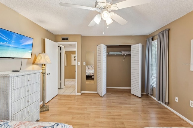 unfurnished bedroom featuring ceiling fan, a closet, a textured ceiling, and light hardwood / wood-style floors