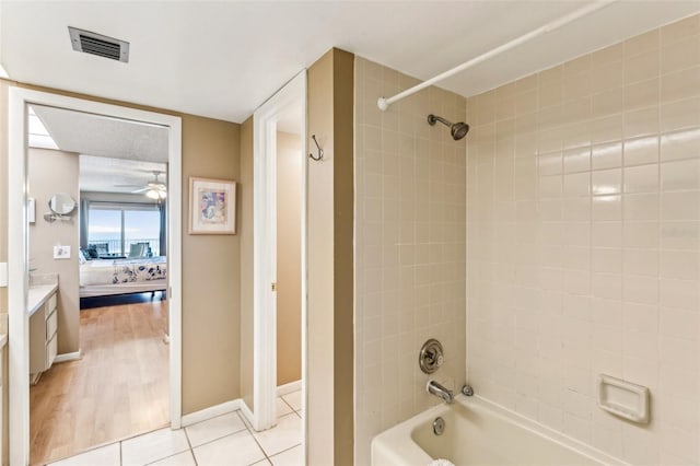 bathroom featuring tile patterned flooring, tiled shower / bath, and vanity