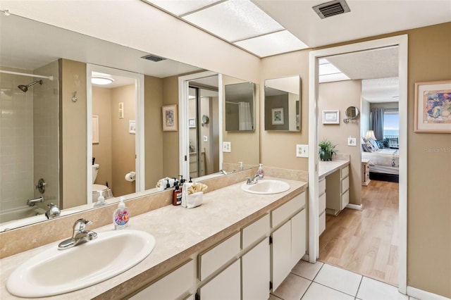 full bathroom with toilet, tile patterned flooring, tiled shower / bath, and vanity