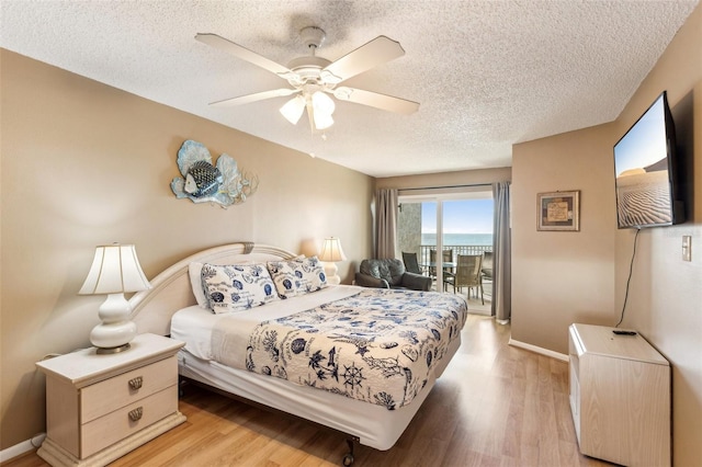 bedroom with light wood-type flooring, ceiling fan, access to exterior, and a textured ceiling