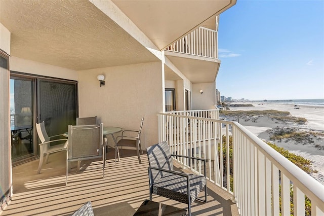 balcony with a water view and a view of the beach