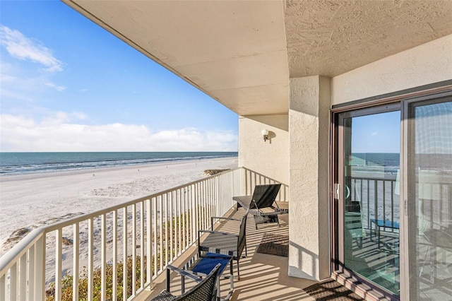 balcony featuring a view of the beach and a water view