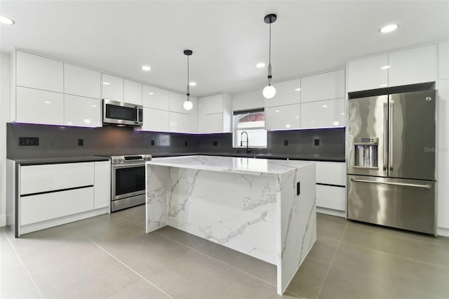 kitchen featuring a center island, light tile patterned floors, hanging light fixtures, and appliances with stainless steel finishes