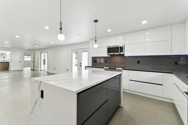 kitchen featuring backsplash, white cabinets, hanging light fixtures, dark stone countertops, and a kitchen island