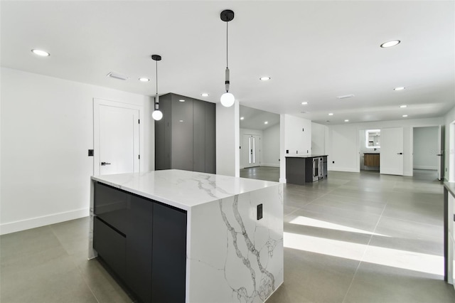 kitchen with pendant lighting, light tile patterned floors, a spacious island, and light stone counters