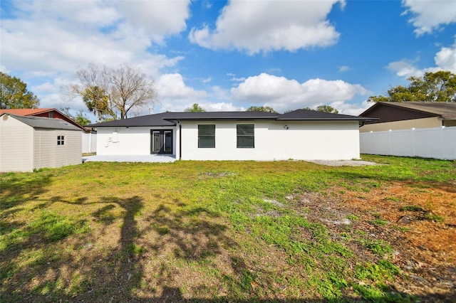 back of property featuring a lawn and a shed