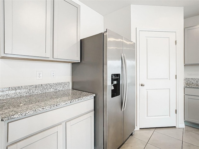 kitchen featuring stainless steel refrigerator with ice dispenser, gray cabinets, light stone counters, and light tile patterned flooring