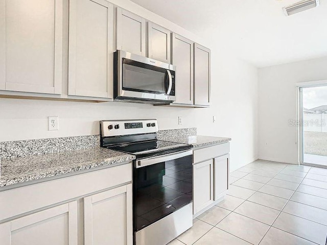 kitchen featuring light stone countertops, light tile patterned floors, and stainless steel appliances