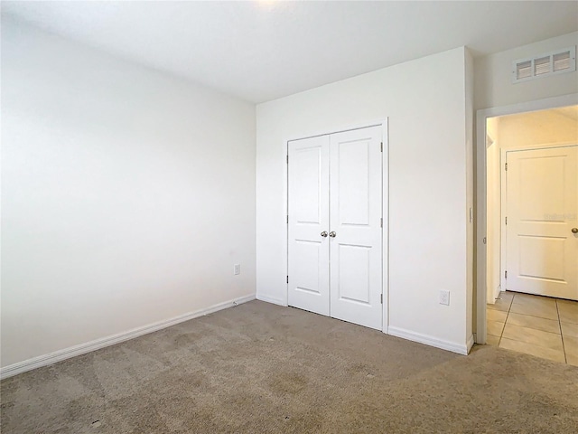 unfurnished bedroom featuring light carpet and a closet