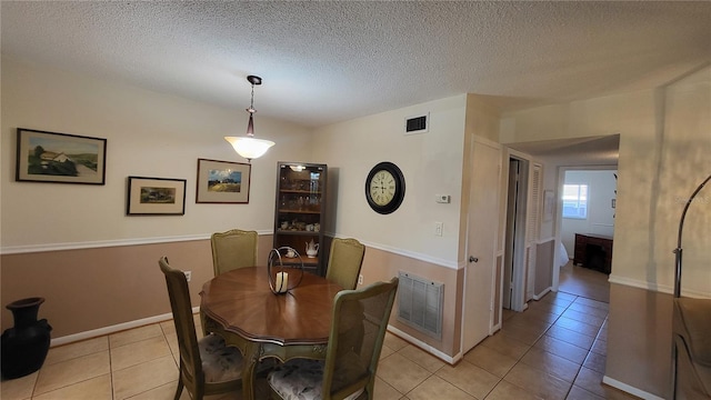 tiled dining space featuring a textured ceiling