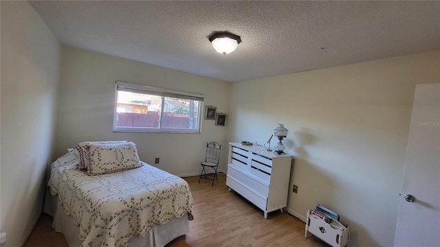 bedroom with a textured ceiling and light hardwood / wood-style floors