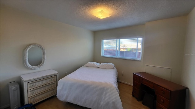 bedroom featuring dark hardwood / wood-style flooring and a textured ceiling