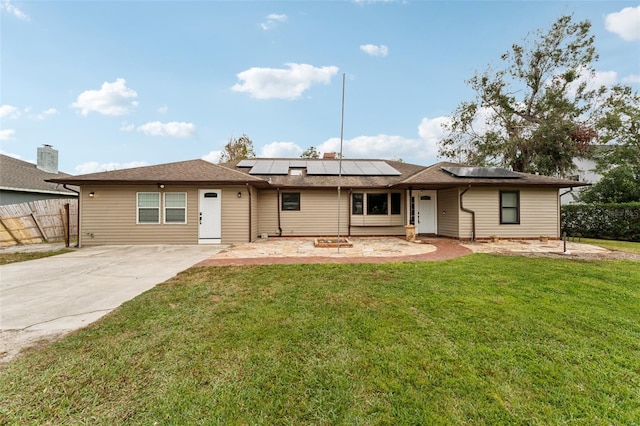 rear view of property with solar panels and a yard