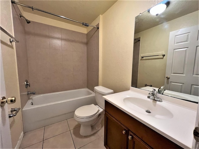 full bathroom with tile patterned floors, vanity, tiled shower / bath, and toilet