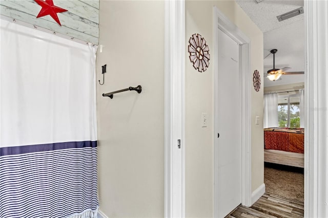 bathroom featuring hardwood / wood-style flooring, ceiling fan, and a textured ceiling