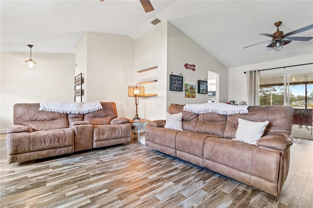 living room featuring a textured ceiling, high vaulted ceiling, ceiling fan, and light wood-type flooring