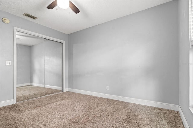 unfurnished bedroom with ceiling fan, a closet, carpet, and a textured ceiling